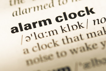 Fototapeta premium Close up of old English dictionary page with word alarm clock