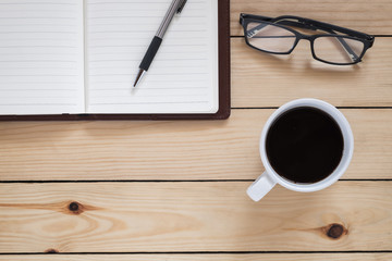 Office desk with notebook, pen,eye glasses and coffee cup.Top view with copy space