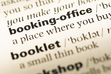 Obraz premium Close up of old English dictionary page with word booking office