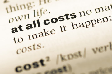 Close up of old English dictionary page with word at all costs