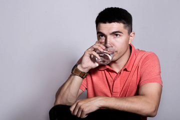 Young man drinking water in studio setting