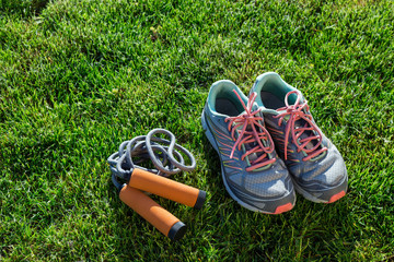 Sports shoes sneakers and jumping rope on grass. Fitness.