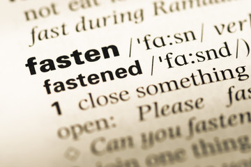 Close up of old English dictionary page with word fasten