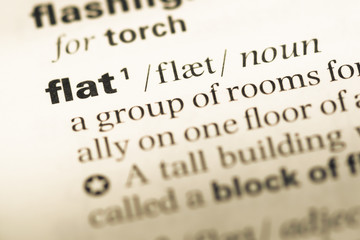 Obraz premium Close up of old English dictionary page with word flat