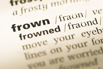 Close up of old English dictionary page with word frown