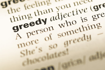 Close up of old English dictionary page with word greedy