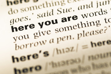 Fototapeta premium Close up of old English dictionary page with word here you are