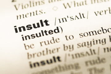 Close up of old English dictionary page with word insult
