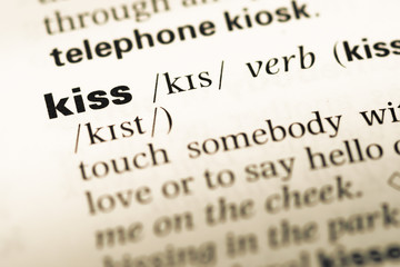 Fototapeta premium Close up of old English dictionary page with word kiss
