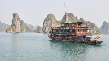 Fototapeta na wymiar Tourist Boat Plying Halong Bay Against Backdrop of Limestone Outcrops - Vietnam