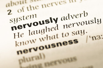 Close up of old English dictionary page with word nervously