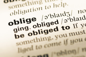 Obraz premium Close up of old English dictionary page with word oblige