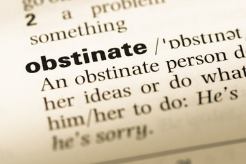 Obraz premium Close up of old English dictionary page with word obstinate