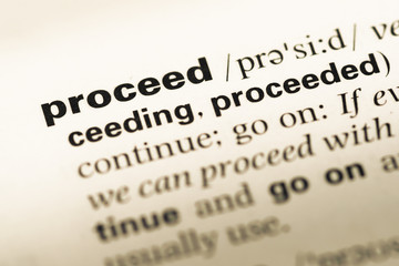 Close up of old English dictionary page with word proceed