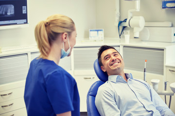 Fototapeta premium happy female dentist with man patient at clinic