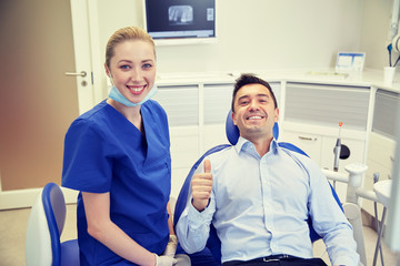 happy female dentist with man patient at clinic