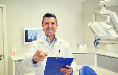 happy dentist pointing to you at dental clinic