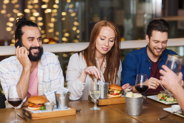 man with smartphone and friends at restaurant