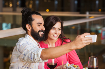 couple taking selfie by smartphone at restaurant