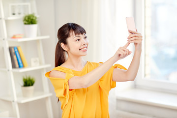happy asian woman taking selfie with smartphone