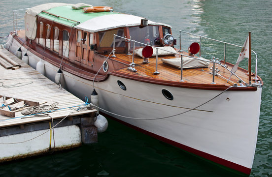 White vintage boat with wooden deck at pier