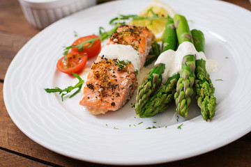 Baked salmon garnished with asparagus and tomatoes with herbs