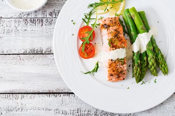 Foto auf Glas Baked salmon garnished with asparagus and tomatoes with herbs. Top view © timolina