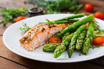 Baked salmon garnished with asparagus and tomatoes with herbs