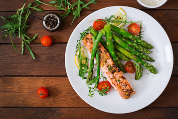Baked salmon garnished with asparagus and tomatoes with herbs. Top view