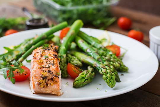 Baked salmon garnished with asparagus and tomatoes with herbs