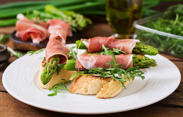 Toasts (sandwich) with asparagus, arugula and prosciutto