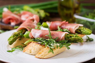 Toasts (sandwich) with asparagus, arugula and prosciutto