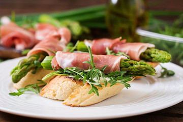 Toasts (sandwich) with asparagus, arugula and prosciutto