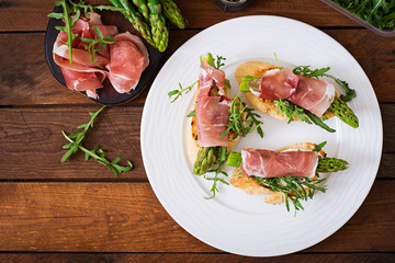 Toasts (sandwich) with asparagus, arugula and prosciutto. Top view