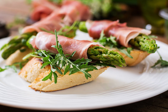 Toasts (sandwich) with asparagus, arugula and prosciutto