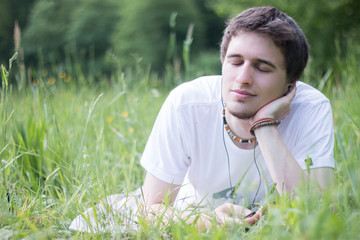 Junger Mann liegt im Gras, nachdenklich