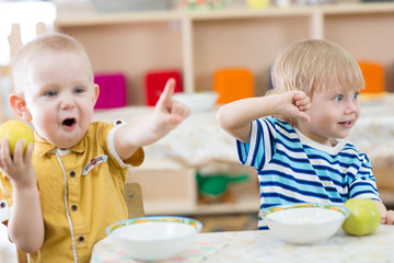 Funny smiling kids feeding in kindergarten