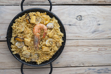 Vegetable paella with seafood on a wooden background
