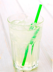 glass of lemonade with straw on wood