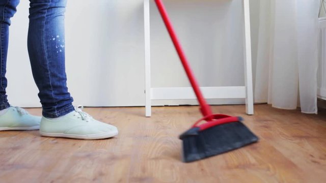 woman with broom cleaning floor at home