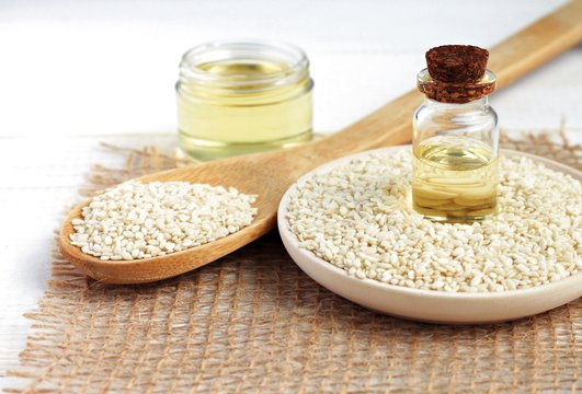 
Sesame oil in bottles, sesame seeds scattered. Culinary and cosmetic use.
