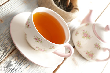 Cup of tea, teapot and dried tea leaves on wooden table
