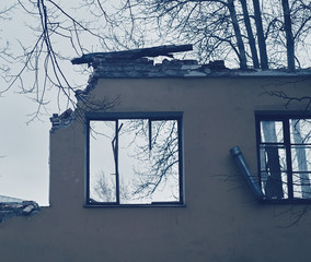 Piece of the wall of ruined house with broken windows, dismantling of building