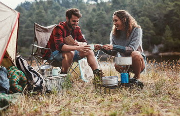 Happy young couple camping by the lake