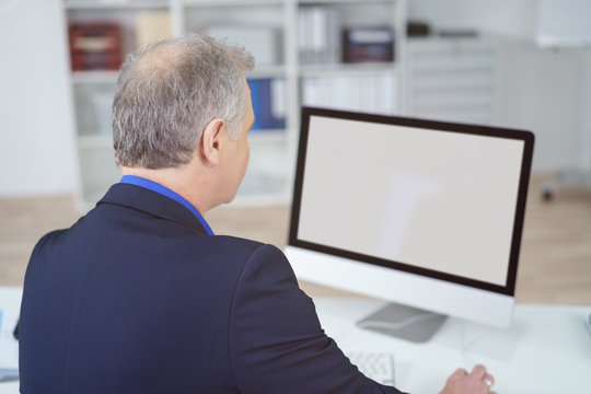 mann im büro schaut auf computer bildschirm