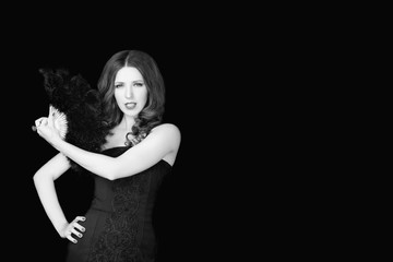 Beautiful woman in black dress holding fan of  feathers on dark background.