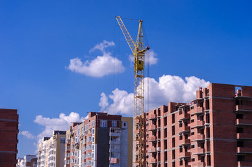 Fototapeta na wymiar Construction of a brick high-rise building with a crane