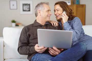 lachendes älteres paar mit laptop und telefon