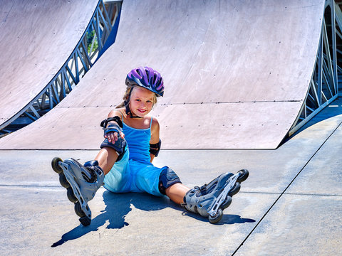 Girl in roller skates sitting on ride in skatepark. girl in fall protection in skatepark.