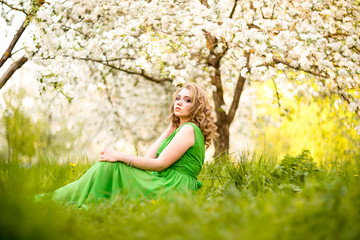Naklejka na ściany i meble Beautiful happy young woman in spring blossoming garden